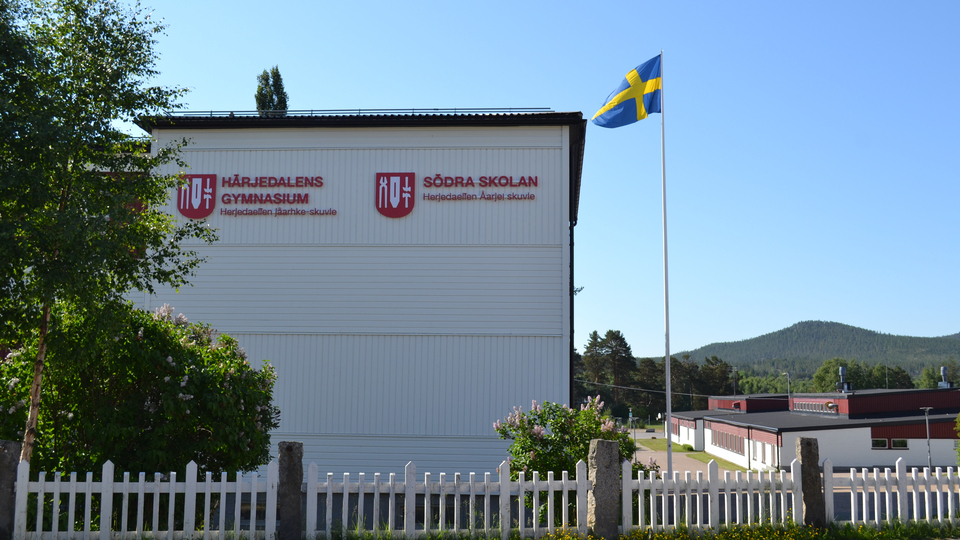 Skyltar med Södra skolan och Härjedalens gymnasium på en vit träbyggnad.