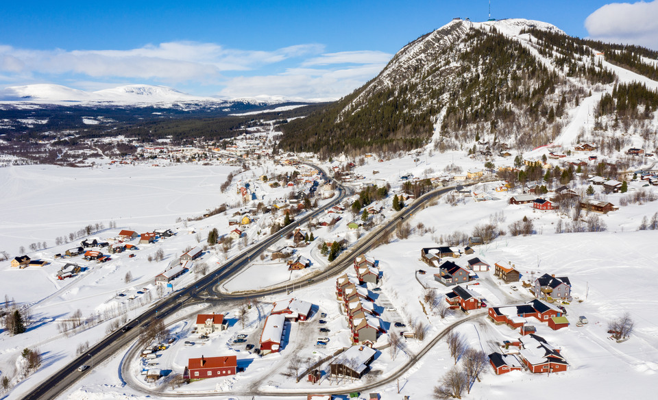 Drönarbild över Funäsdalen med Funäsdalsberget i fonden. Villor och vägar mellan snötäckt sjö och skogsklätt berg med snötäckta backar.