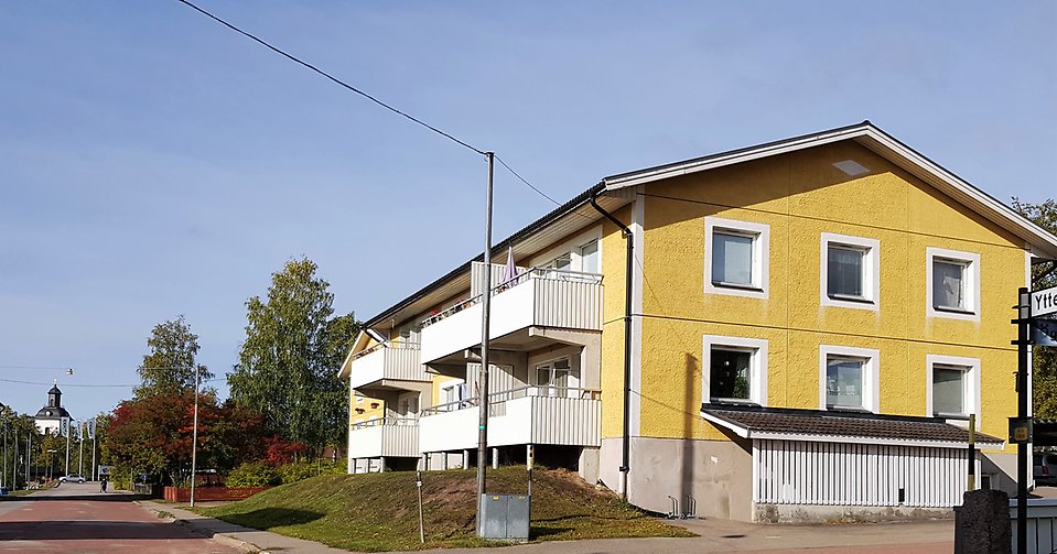 Ett gult flerfamiljshus med två våningar och vita balkonger. 