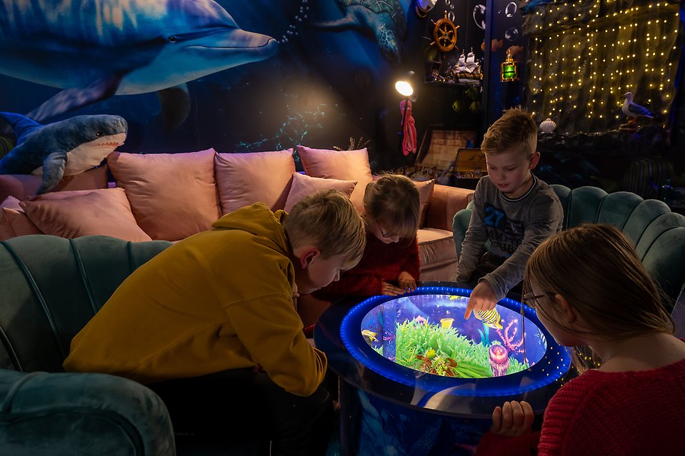 Fyra barn sitter och tittar i tittskåpet i aquarummet.